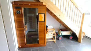 Un ascensor de madera con puerta de vidrio, una pequeña mesa de madera con una cesta, y un carrito de juguete.