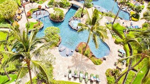 Un resort con varias piscinas, palmeras y zonas de descanso.