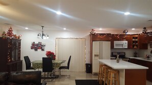 Une cuisine moderne avec des meubles en bois, un réfrigérateur blanc, un four à micro-ondes et un coin repas comprenant une table et des chaises.
