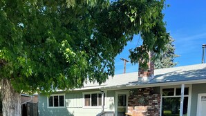A two-story house with a front porch, a brick chimney, and a well-maintained lawn.