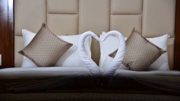 Un letto con un asciugamano disposto a forma di cuore e due cuscini decorativi.
