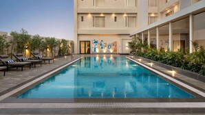 Ein Swimmingpool mit Liegestühlen und ein Gebäude im Hintergrund, das eine Wandmalerei zeigt.