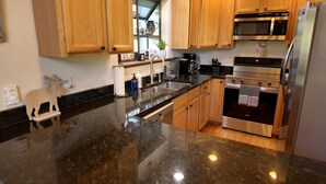 Una cocina con armarios de madera, un refrigerador de acero inoxidable, un microondas, un horno y un lavamanos.