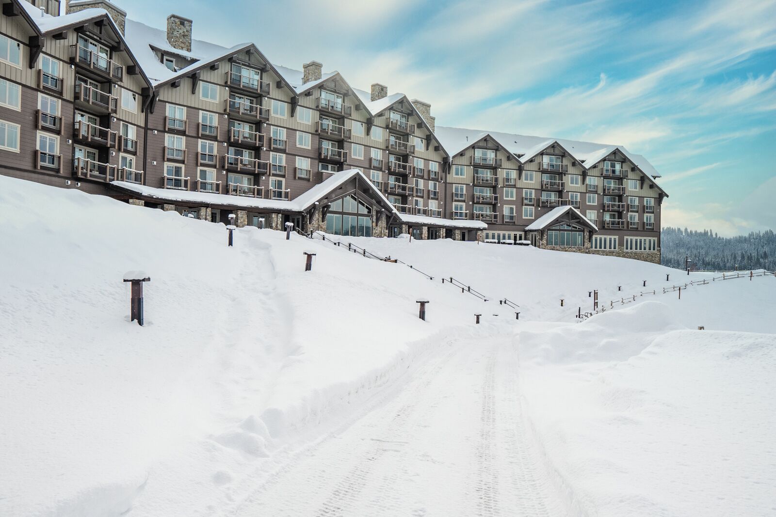 A multi-story lodge with a ski slope leading to the entrance, surrounded by snow.