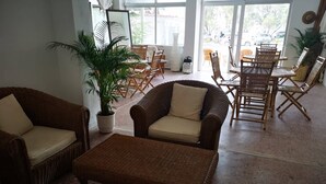 Un espacio interior amplio con muebles de mimbre, incluyendo sofás y sillones, y una planta en maceta.