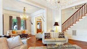 A spacious living room with a chandelier, leather sofas, a glass coffee table, and a staircase. - Heated Pool Access | 5*Clean | Flex Cancelation (Savannah)