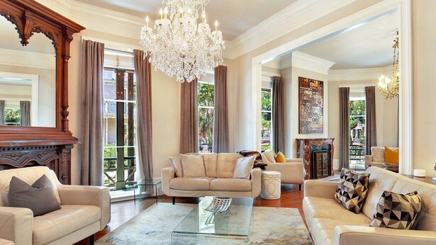 A spacious living room with a chandelier, leather sofas, a glass coffee table, and a fireplace. - Heated Pool Access | 5*Clean | Flex Cancelation (Savannah)