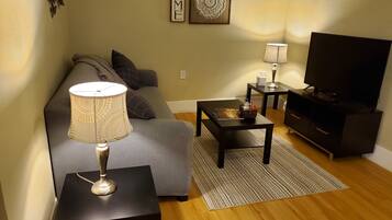 A living room with a sofa, a coffee table, a TV stand, and a lamp.