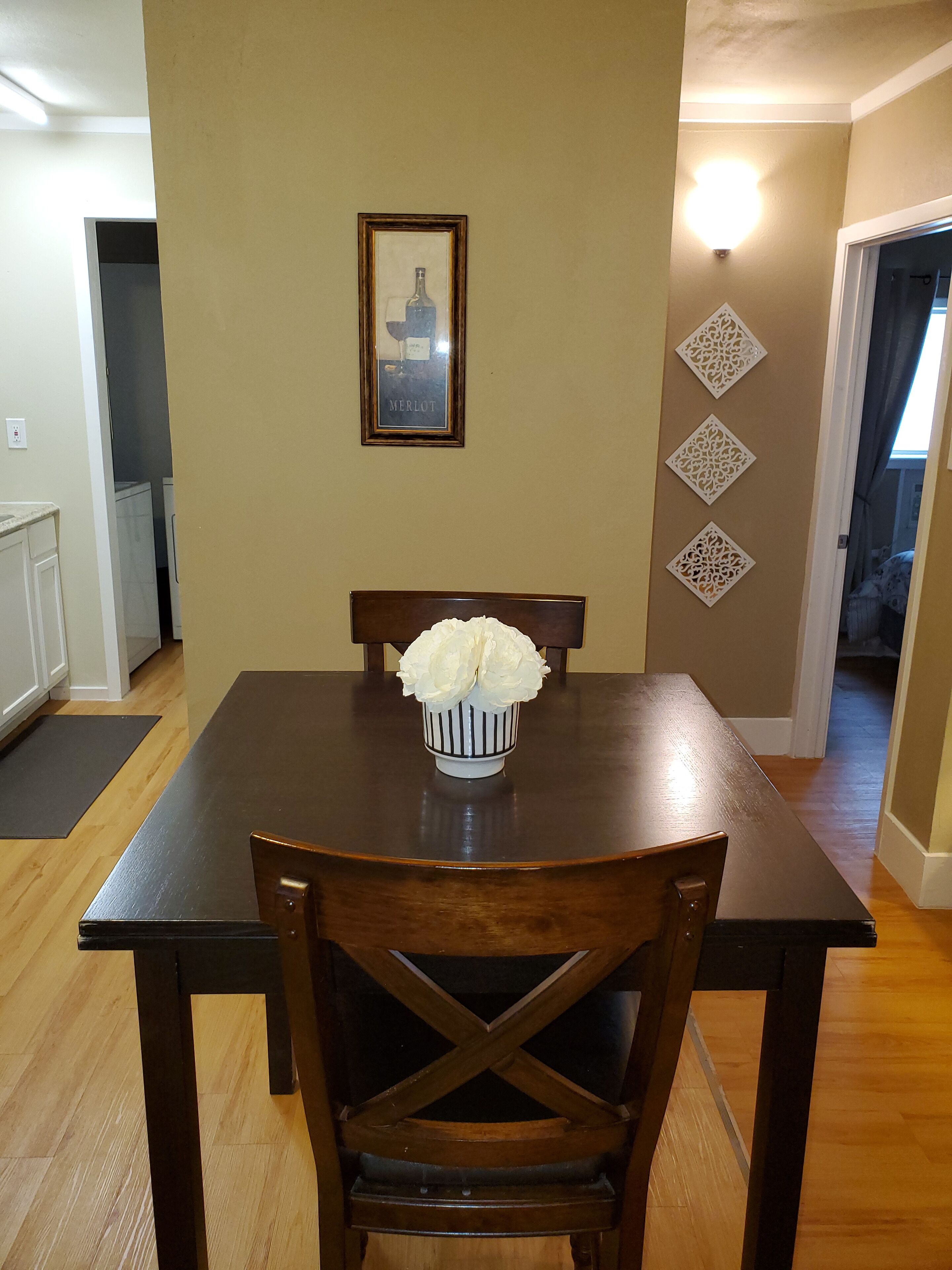A dining table with a vase of flowers, a framed picture on the wall, and decorative wall panels.
