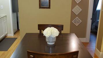 A dining table with a vase of flowers, a framed picture on the wall, and decorative wall panels.