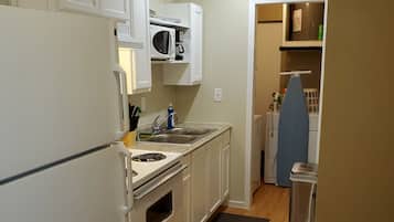 A compact kitchen with white cabinets, a microwave, a stove, and a sink.