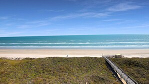 Una playa con un paseo marítimo de madera que lleva a una estructura en la orilla.