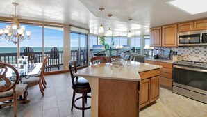 Una cocina moderna con una isla grande, armarios de madera y vistas al océano.