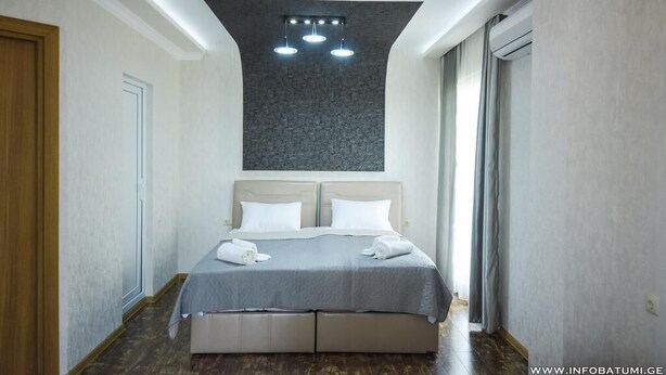 Una habitación de hotel moderna con una cama grande, una lámpara de techo y una ventana con cortinas.