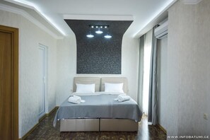 Et moderne hotelværelse med en stor seng, en lampe i loftet og et vindue med gardiner.
