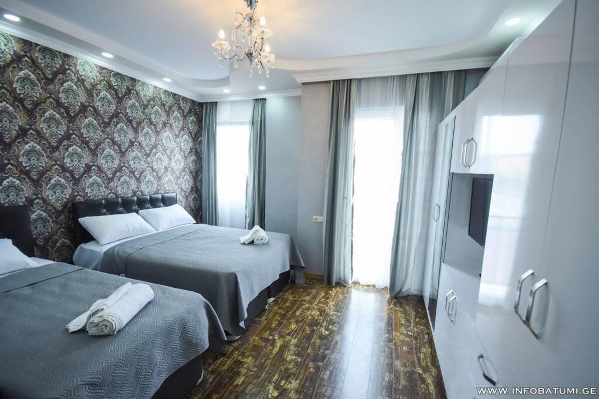 A hotel room with two beds, a chandelier, and a large wardrobe.