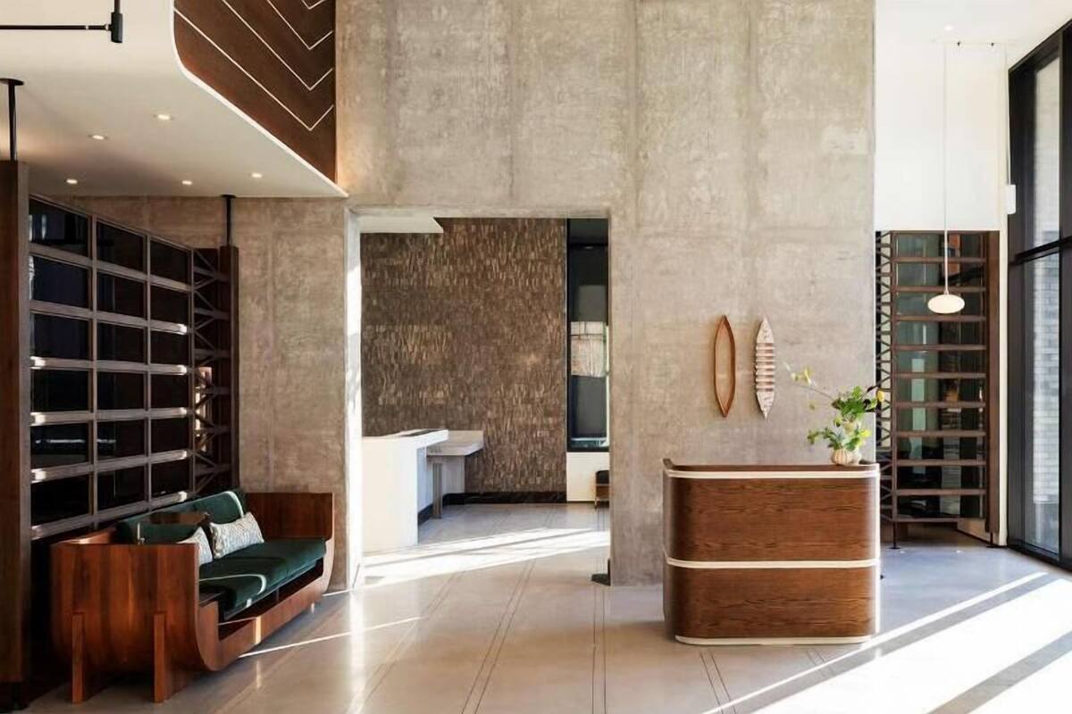 A modern lobby with a reception desk, a green sofa, and a wooden bench.