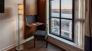 A corner room with a view of a river, a desk, a chair, and a floor lamp. - Thompson Washington D.C., by Hyatt (Washington)