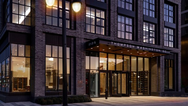 Un edificio moderno con fachada de ladrillo, ventanas grandes y un letrero que dice "221 THOMPSON WASHINGTON DC".