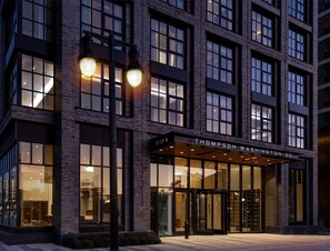 Un edificio moderno con fachada de ladrillo, ventanas grandes y un letrero que dice "221 THOMPSON WASHINGTON DC".