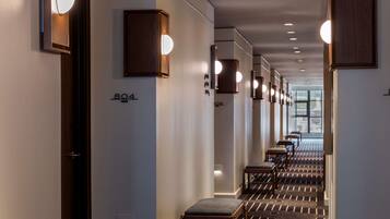 A hotel hallway with a check-in counter, numbered room signs, and a patterned carpet.