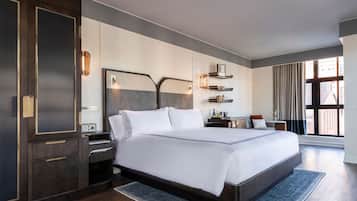 Ein modernes Hotelzimmer mit einem großen Bett, einem Schreibtisch, einem Stuhl und einem fensterbepflanzten Fenster.