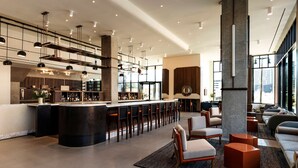 Un área de bar moderna con una isla central, taburetes de bar y un espacio de estar con sofás y sillones.