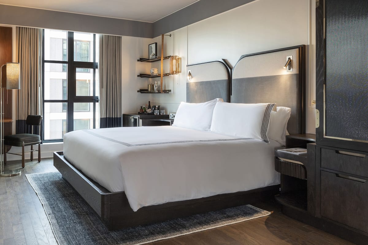 A modern hotel room with a large bed, bedside tables, a desk, and a chair.