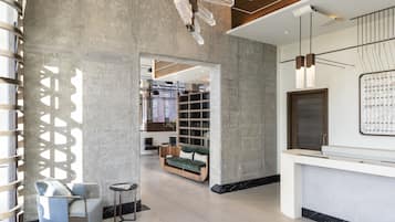 A modern lobby with a grey sofa, a small round table, and a reception desk.