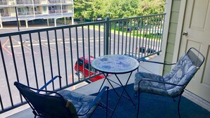 A balcony with two chairs and a table, overlooking a parking area and a building with multiple balconies. - Beautiful Updated Condo With Direct River View From Balcony!  We Love Dogs! (New Braunfels)