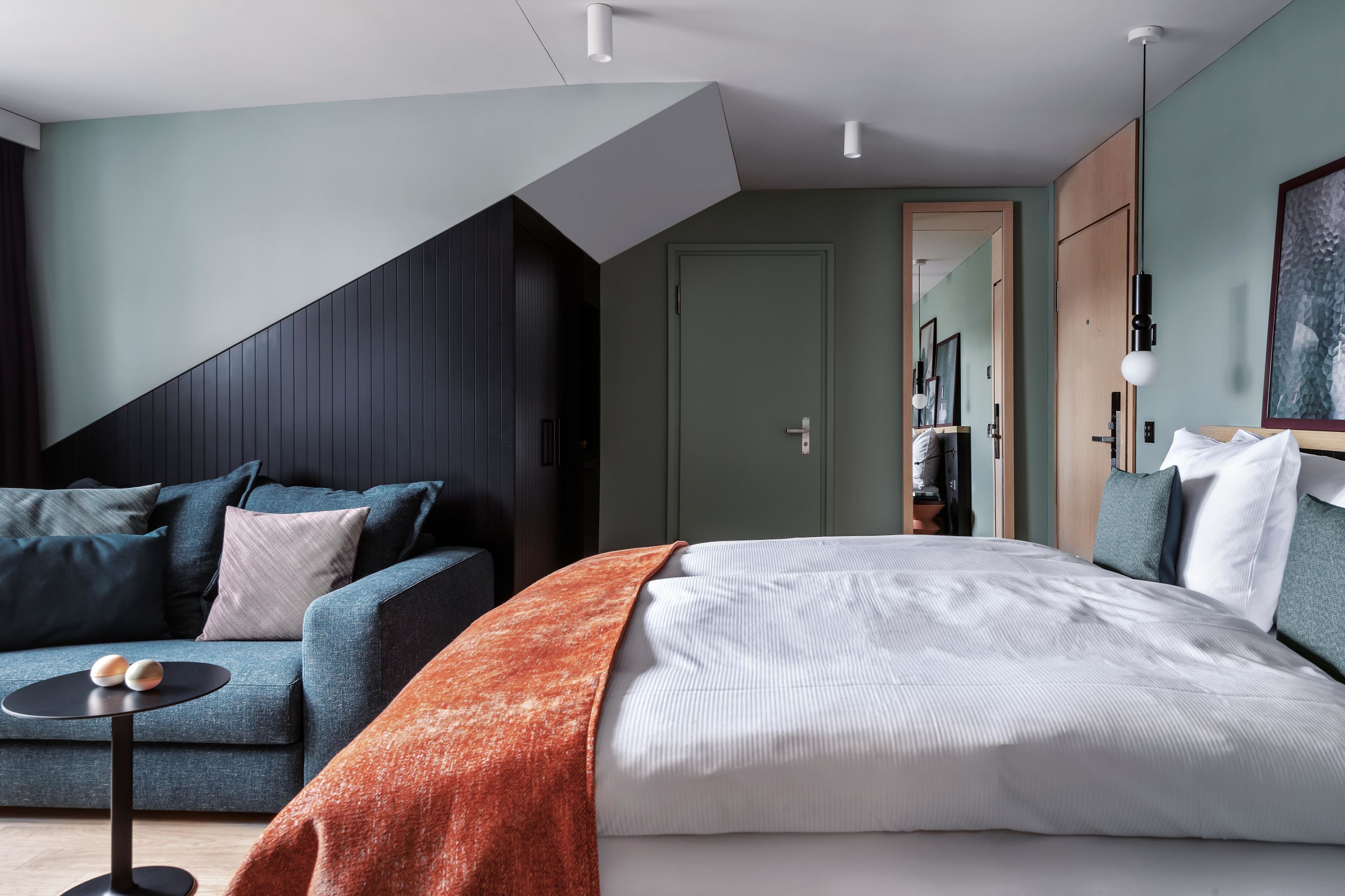 A modern bedroom with a bed, a sofa, and a small table.