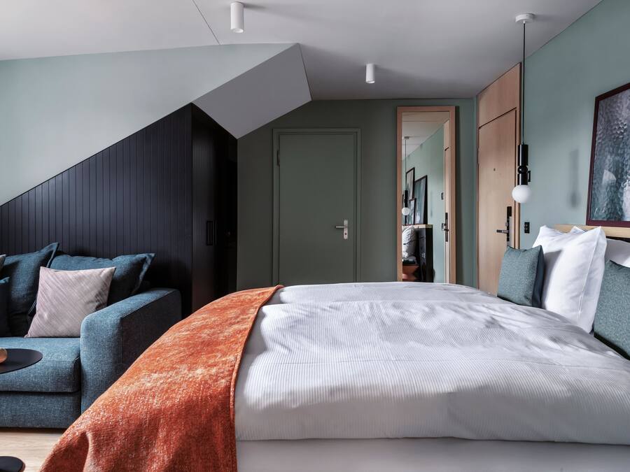 A modern bedroom with a bed, a sofa, and a small table.