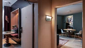 Une chambre d’hôtel moderne avec un intérieur en bois, un coin repas comprenant une table ronde et des chaises, et un numéro de chambre bien visible.