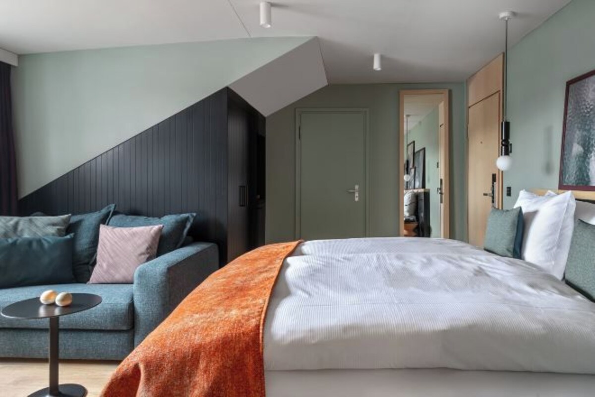 Un dormitorio moderno con una cama, un sofá y una mesita.