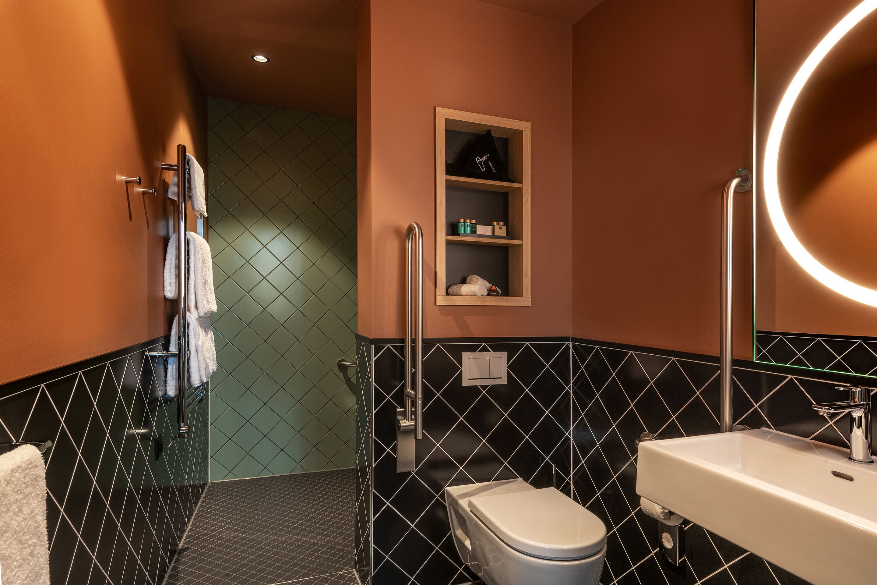 A modern bathroom with a black and white tiled wall, a white sink, and a toilet.