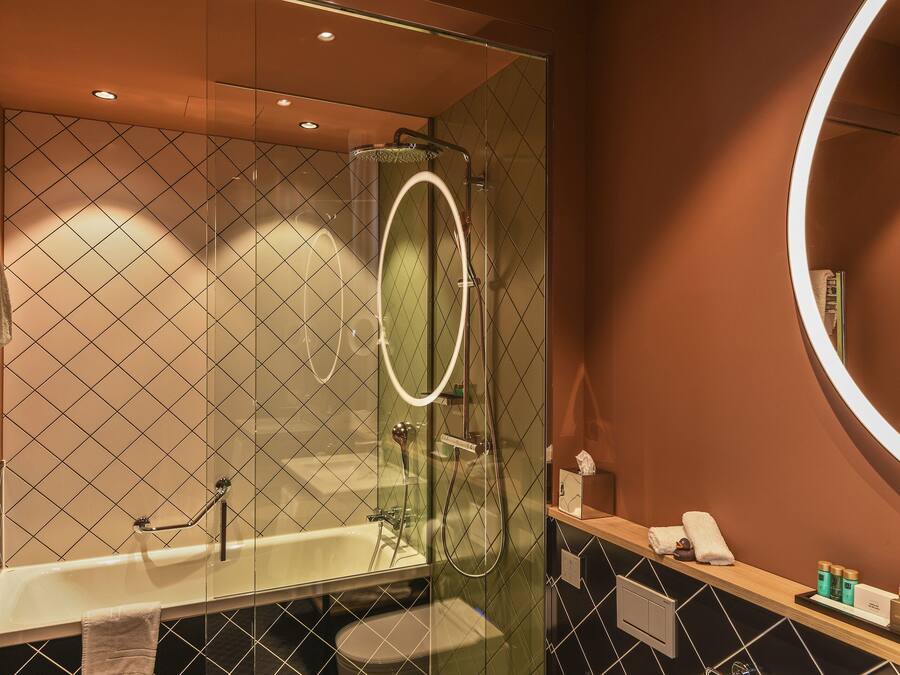A modern bathroom with a glass-enclosed shower, a bathtub, and a vanity with toiletries.