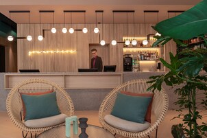 A modern bar area with wicker chairs, a neon sign, and a bar counter with a coffee machine.