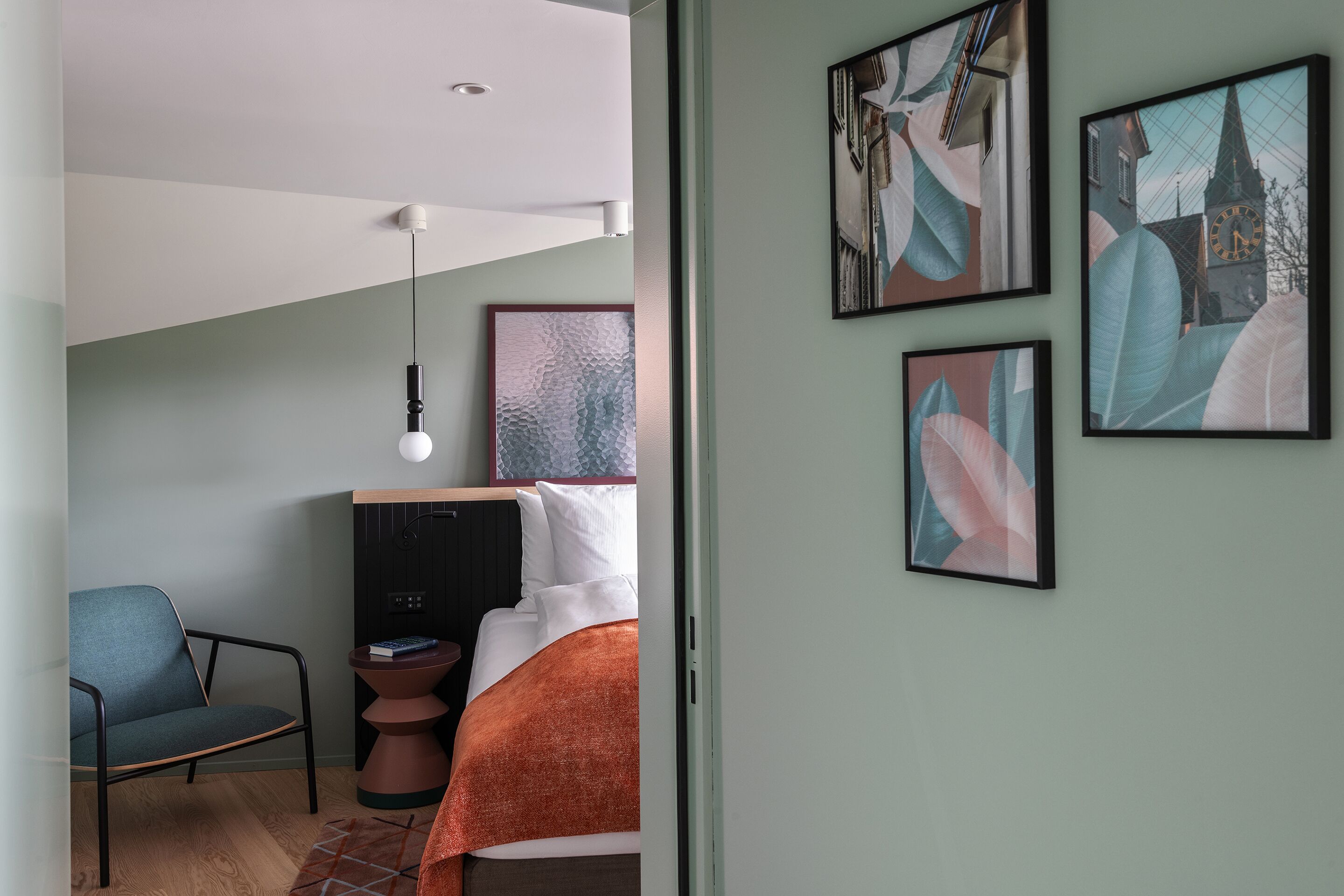 Ein modernes Schlafzimmer mit einem Bett, einem Sessel und Bildern an der Wand.