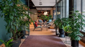 A modern interior with a seating area, bookshelves, and potted plants. - Sorell Boutique-Hotel St. Peter Zürich (Zürich)
