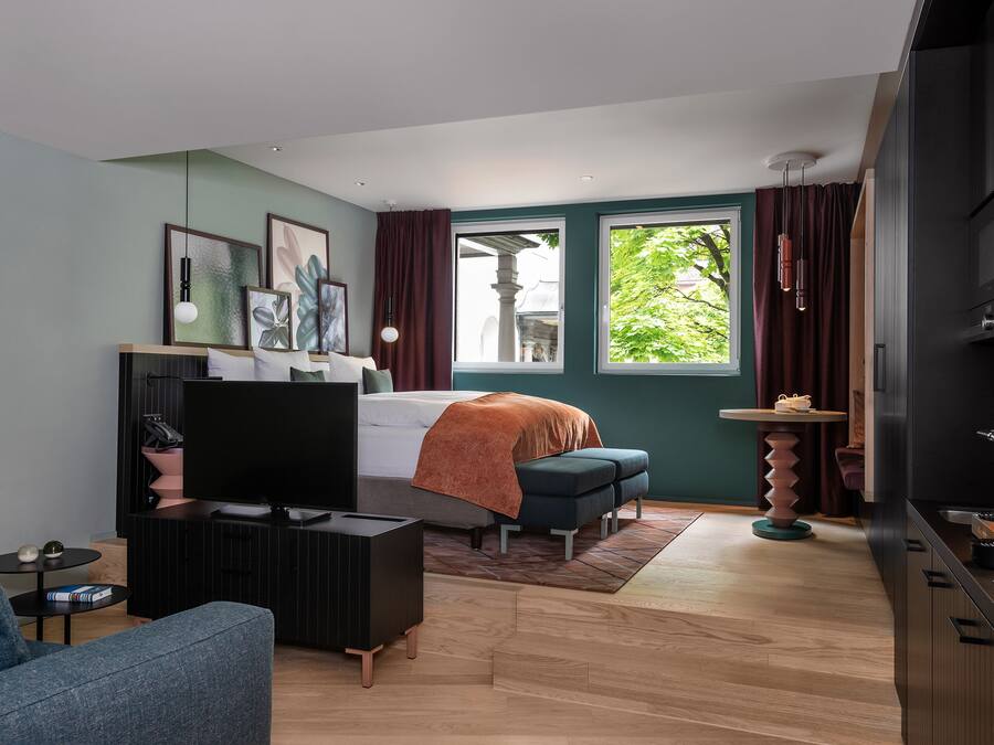 Un dormitorio moderno con cama, televisión y zona de estar.
