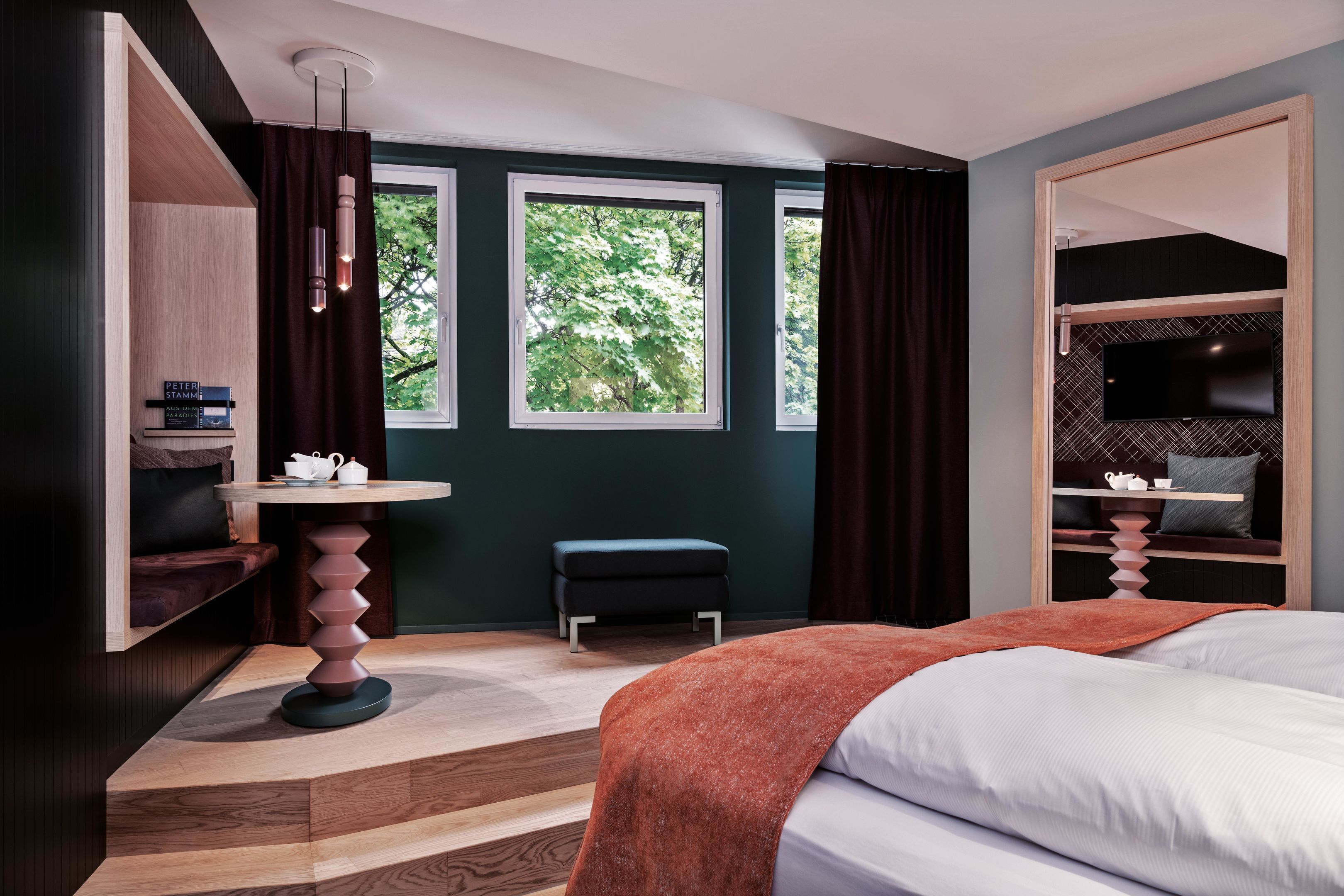 A modern bedroom with a bed, a desk, a chair, and a TV.