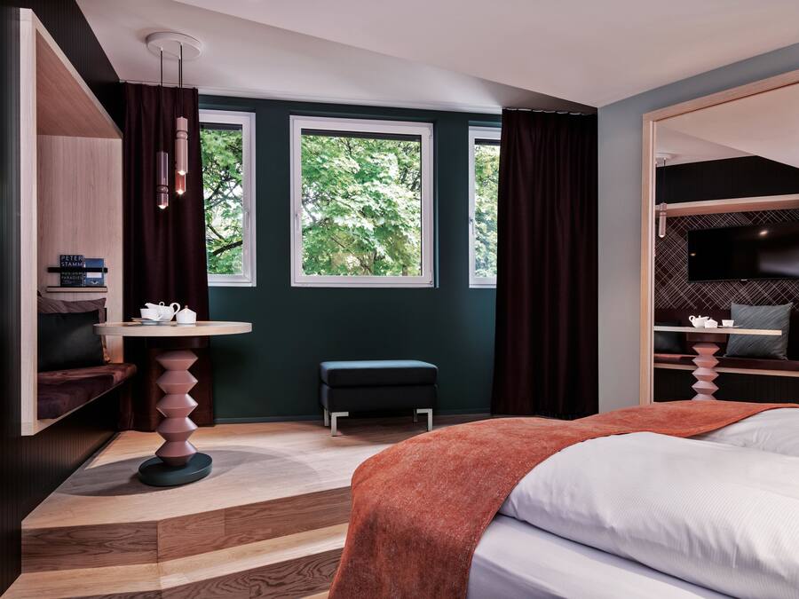 A modern bedroom with a bed, a desk, a chair, and a TV.