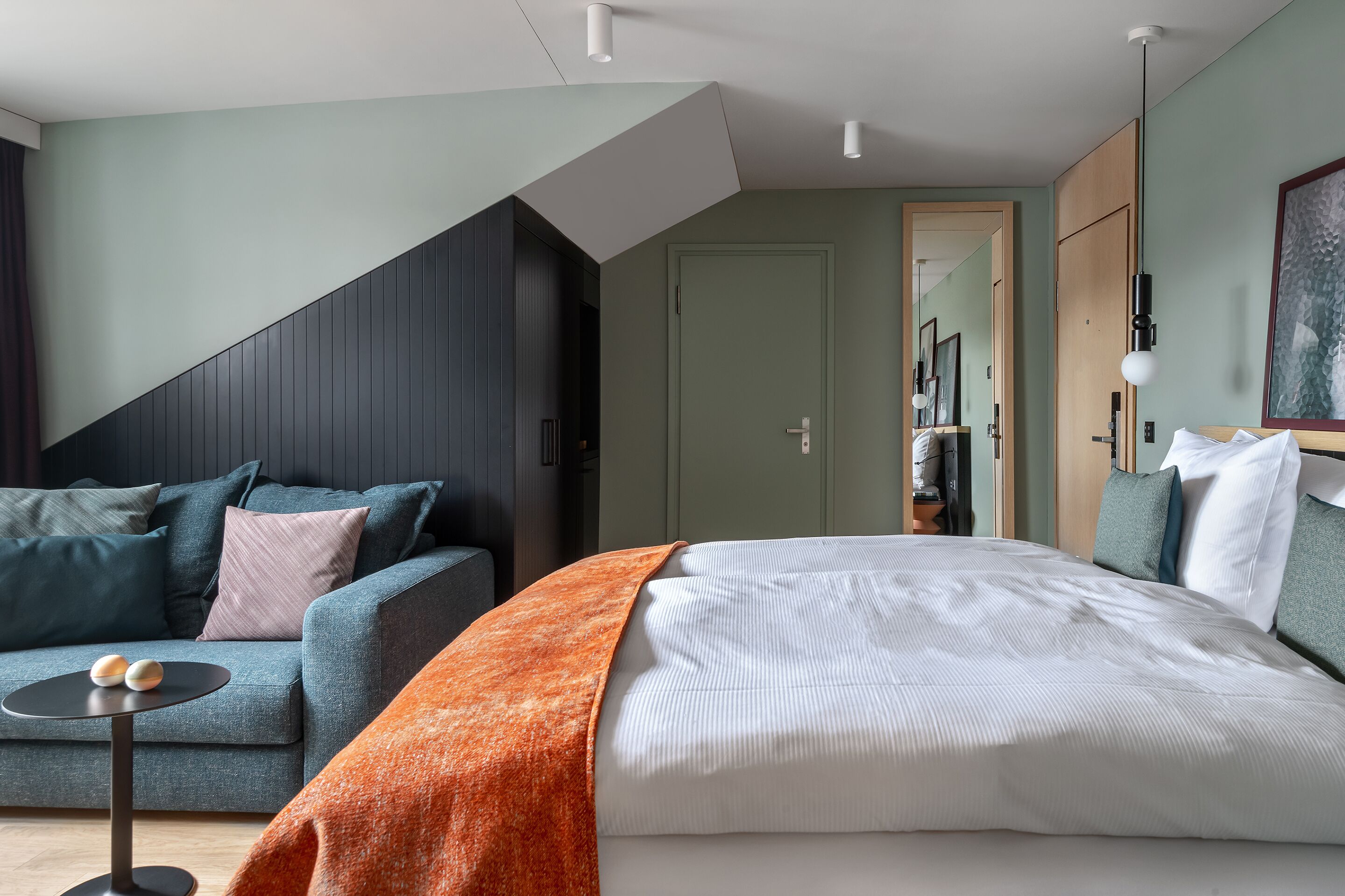 Ett modernt hotellrum med en säng, en soffa, ett litet bord och en garderob.