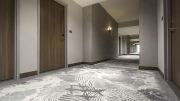 A hallway with carpeted floors, wooden doors, and light fixtures.
