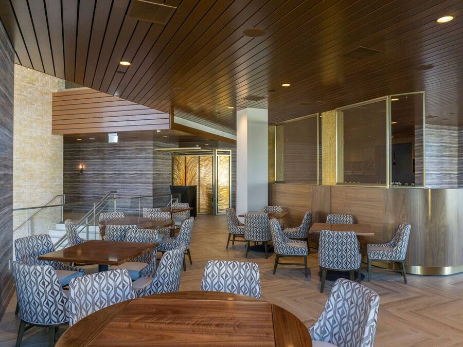 A modern interior with wooden panel ceilings, patterned seating, and a central bar area.
