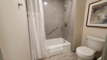 A bathroom with a bathtub, toilet, and shower curtain.