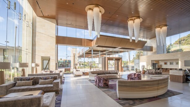 A spacious lobby with modern furniture, large windows, and a high ceiling with hanging lights. - Legacy Resort Hotel & Spa (San Diego)