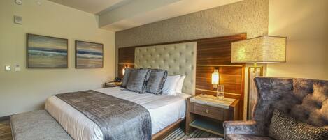 Een hotelkamer met een groot bed, een slaapbank, een nachtkastje en een lamp.