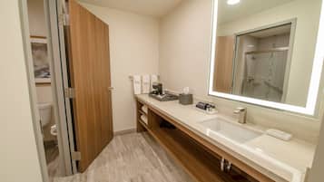 Un baño moderno con tocador de madera, un espejo grande y zona de ducha.
