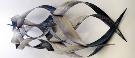 A wall-mounted abstract sculpture with interwoven metallic and wooden elements.
